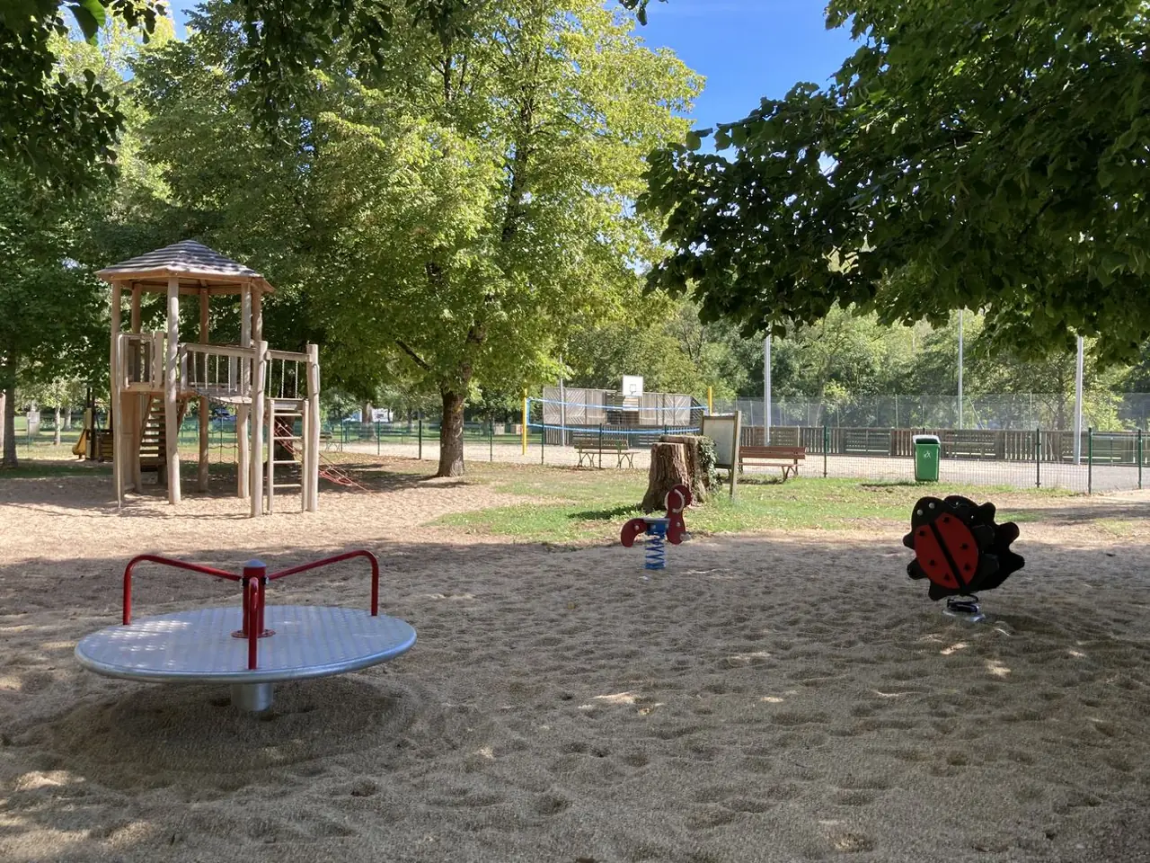 Aire de jeux du lac de Catus dans le Lot : structure bois, tourniquet et jeux à ressort sous les arbres